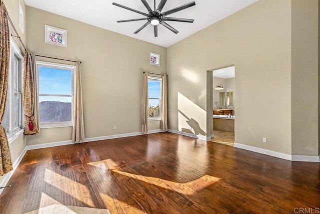 unfurnished room with ceiling fan, a wealth of natural light, and dark hardwood / wood-style floors