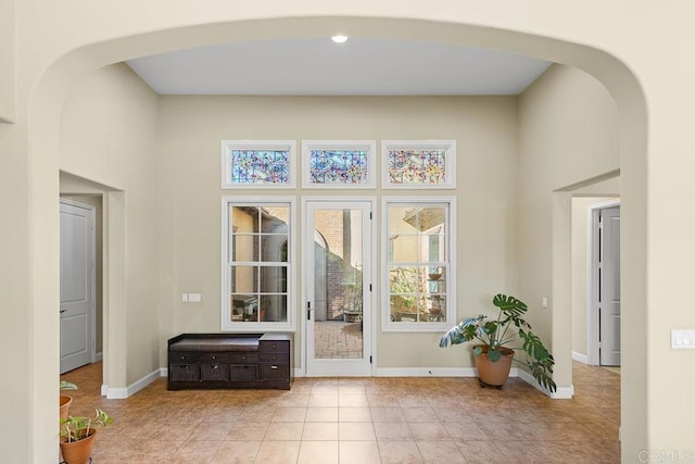 doorway with light tile patterned floors and a high ceiling