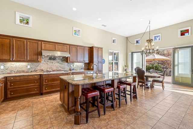 kitchen with an inviting chandelier, light tile patterned flooring, a breakfast bar area, and a kitchen island with sink