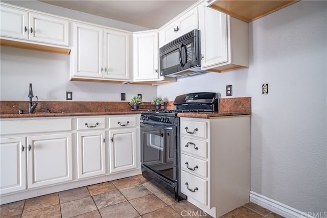 kitchen featuring a sink, white cabinetry, baseboards, dark stone counters, and black appliances