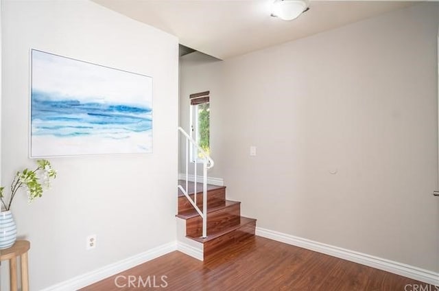 empty room featuring stairs, wood finished floors, and baseboards