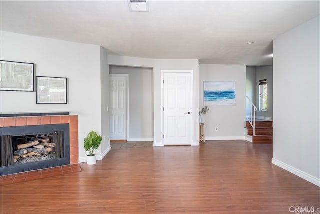 unfurnished living room featuring baseboards, visible vents, a tiled fireplace, and wood finished floors