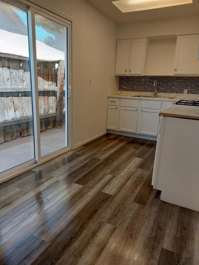 kitchen featuring dark hardwood / wood-style flooring, backsplash, white cabinetry, and sink