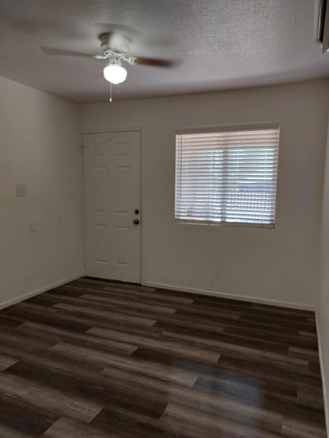 unfurnished room with a textured ceiling, ceiling fan, and dark wood-type flooring