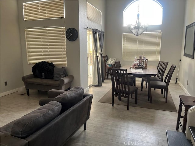 dining area featuring a notable chandelier, a high ceiling, and light wood-type flooring