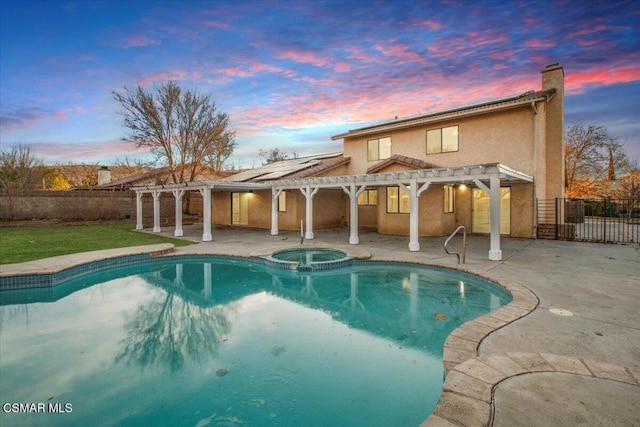 pool at dusk featuring an in ground hot tub, a pergola, and a patio area