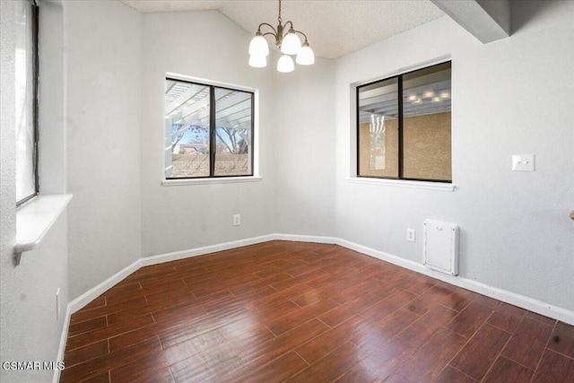 spare room featuring a chandelier, dark hardwood / wood-style floors, and lofted ceiling