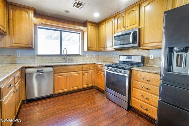 kitchen featuring sink, stainless steel appliances, tasteful backsplash, light stone counters, and dark hardwood / wood-style flooring