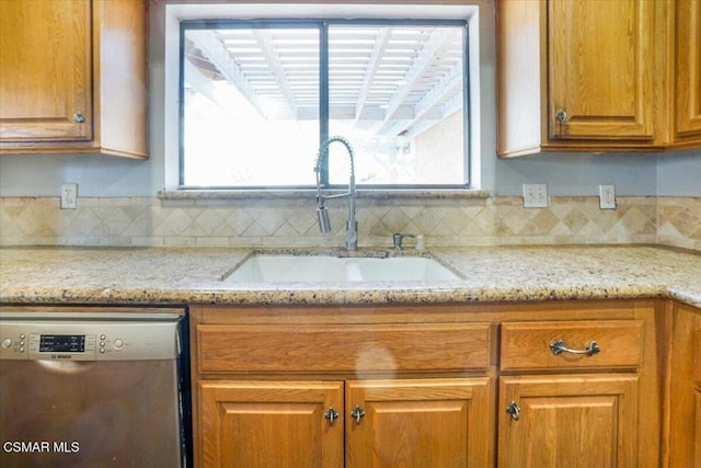 kitchen featuring light stone countertops, stainless steel dishwasher, a healthy amount of sunlight, and sink