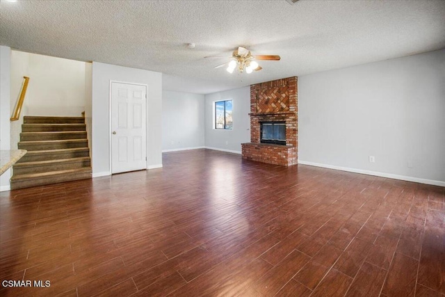 unfurnished living room with a textured ceiling, ceiling fan, dark hardwood / wood-style floors, and a brick fireplace