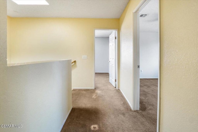 corridor with light colored carpet and a textured ceiling