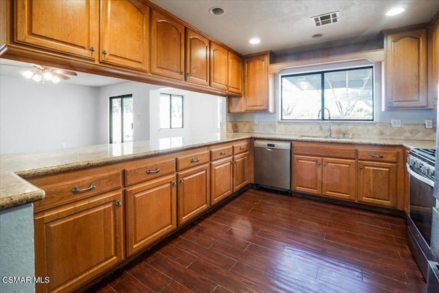 kitchen with kitchen peninsula, appliances with stainless steel finishes, dark hardwood / wood-style flooring, and a wealth of natural light