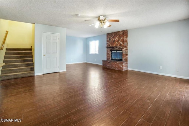 unfurnished living room with a textured ceiling, a fireplace, ceiling fan, and dark wood-type flooring