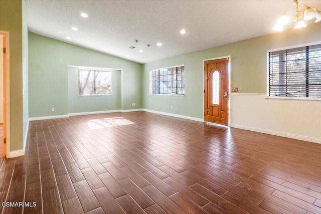 interior space featuring a chandelier, a textured ceiling, vaulted ceiling, and dark wood-type flooring