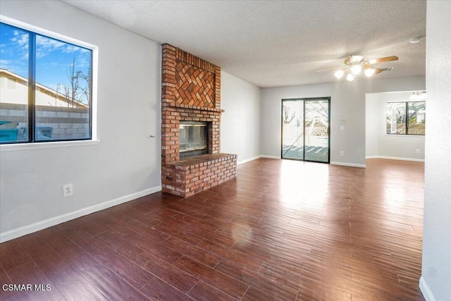 unfurnished living room featuring a textured ceiling, ceiling fan, a fireplace, and dark wood-type flooring