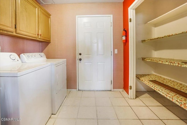 laundry area featuring independent washer and dryer, cabinets, and light tile patterned floors