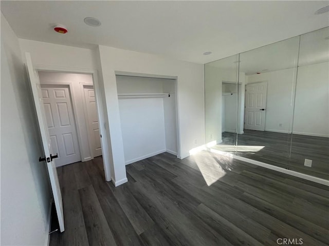 unfurnished bedroom featuring a closet and dark wood-type flooring