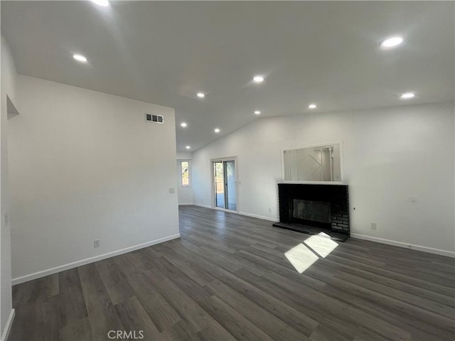 unfurnished living room featuring dark hardwood / wood-style flooring, lofted ceiling, and a brick fireplace