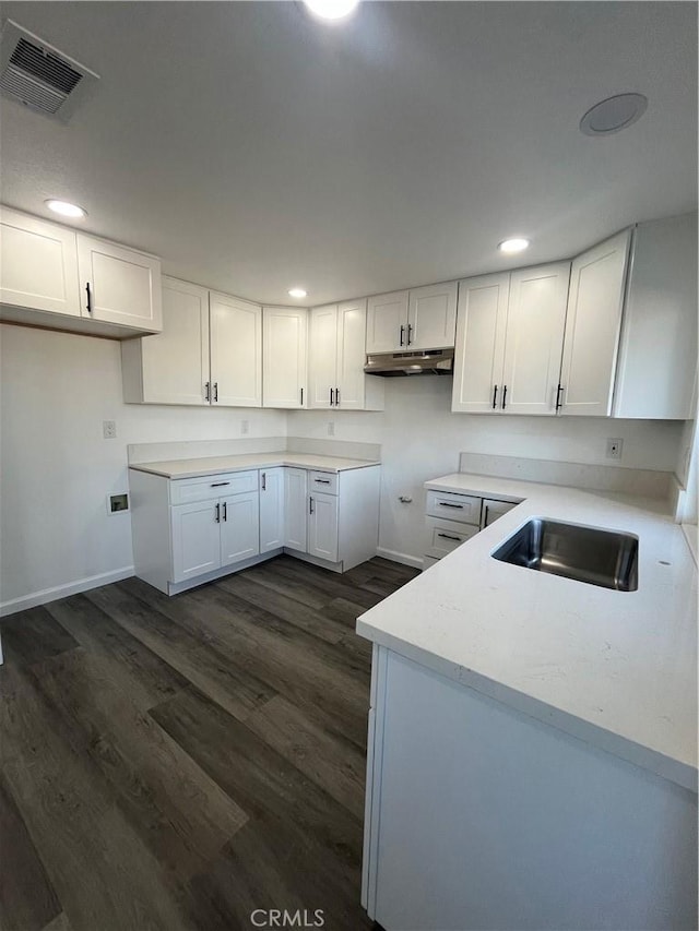 kitchen with light stone countertops, sink, white cabinets, and dark hardwood / wood-style floors