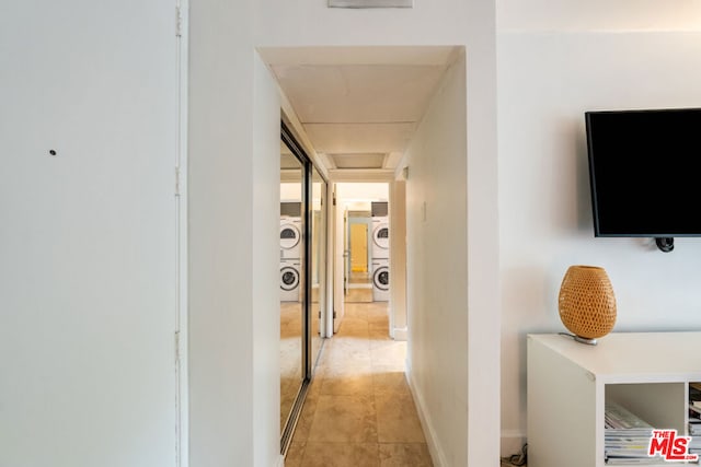 hall with light tile patterned floors and stacked washer and clothes dryer