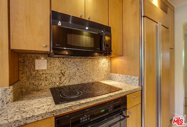 kitchen featuring black appliances, light stone counters, and backsplash