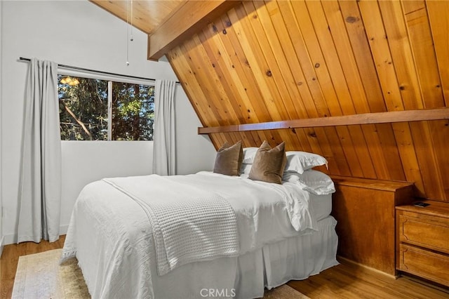 bedroom with lofted ceiling with beams and light hardwood / wood-style floors