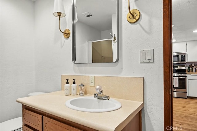 bathroom featuring hardwood / wood-style flooring, vanity, an enclosed shower, and toilet