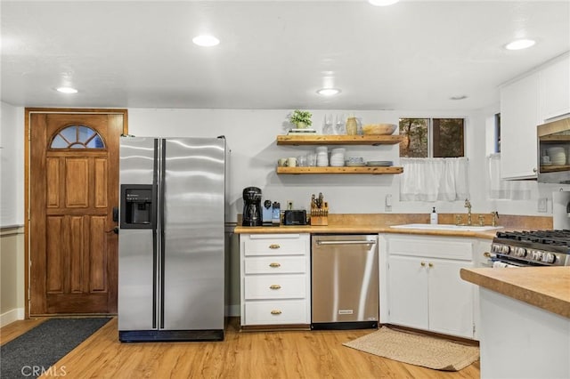 kitchen featuring stainless steel appliances, white cabinetry, and light hardwood / wood-style flooring