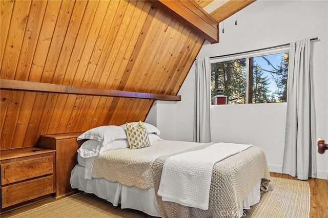 bedroom featuring light hardwood / wood-style floors and vaulted ceiling with beams