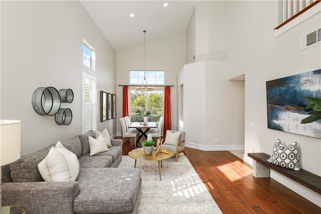 living room with high vaulted ceiling, hardwood / wood-style floors, and a notable chandelier