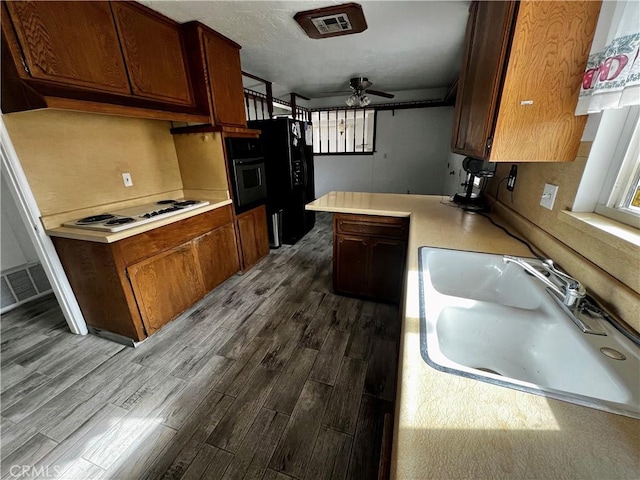 kitchen featuring sink, ceiling fan, black appliances, dark hardwood / wood-style flooring, and kitchen peninsula