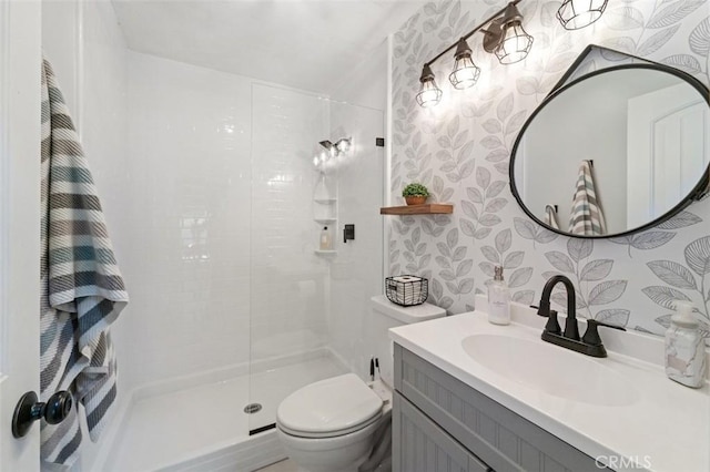 bathroom featuring a tile shower, vanity, and toilet