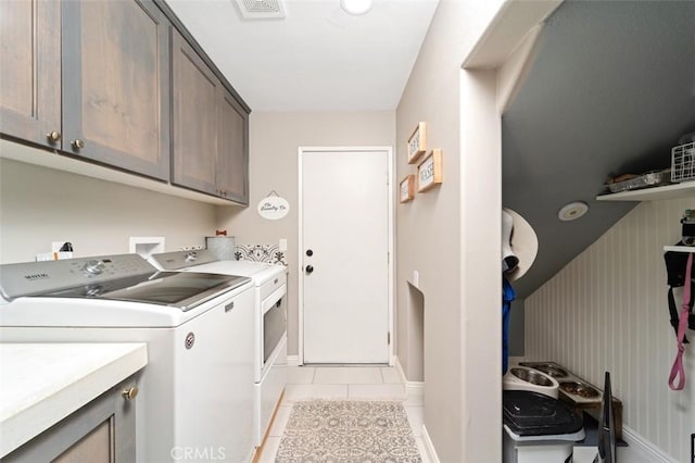 washroom with cabinets, light tile patterned floors, and washing machine and clothes dryer