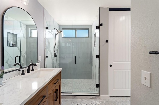 bathroom featuring vanity, a healthy amount of sunlight, and a shower with shower door