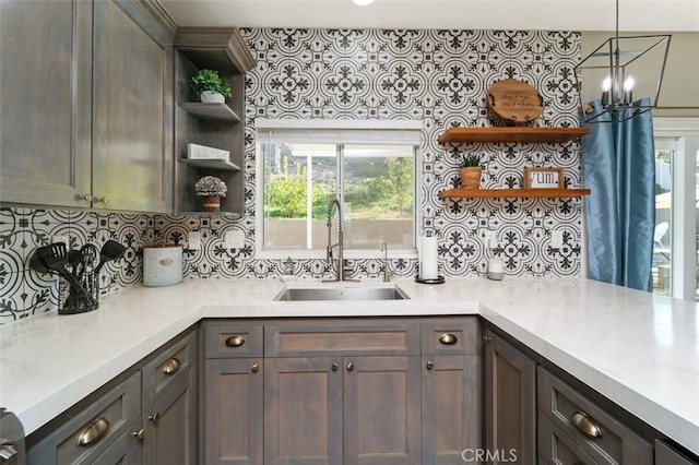 kitchen featuring kitchen peninsula, tasteful backsplash, dark brown cabinets, sink, and hanging light fixtures