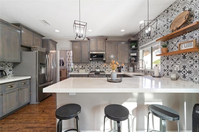 kitchen featuring a kitchen bar, appliances with stainless steel finishes, dark wood-type flooring, sink, and pendant lighting