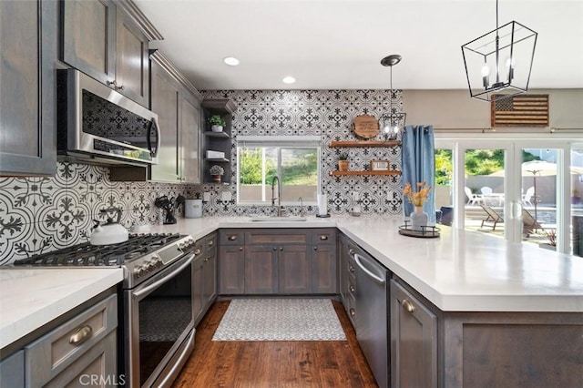 kitchen featuring dark wood-type flooring, a healthy amount of sunlight, pendant lighting, and stainless steel appliances