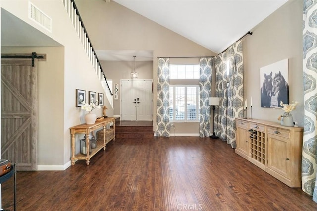 foyer featuring a barn door, dark hardwood / wood-style floors, and high vaulted ceiling