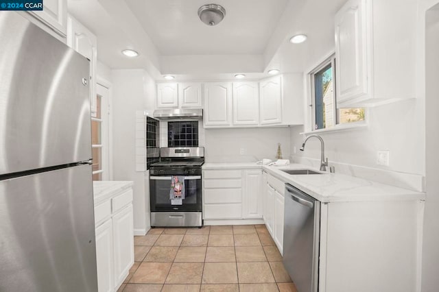 kitchen with sink, light tile patterned flooring, white cabinetry, appliances with stainless steel finishes, and light stone counters