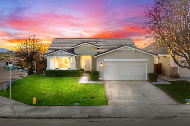 view of front of home featuring driveway, an attached garage, fence, a front lawn, and stucco siding