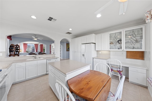 kitchen featuring white appliances, sink, white cabinets, a kitchen island, and light tile patterned flooring