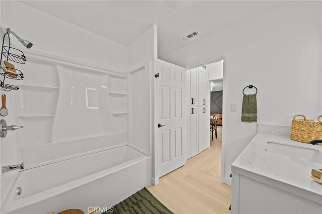 bathroom with washtub / shower combination, wood-type flooring, and vanity