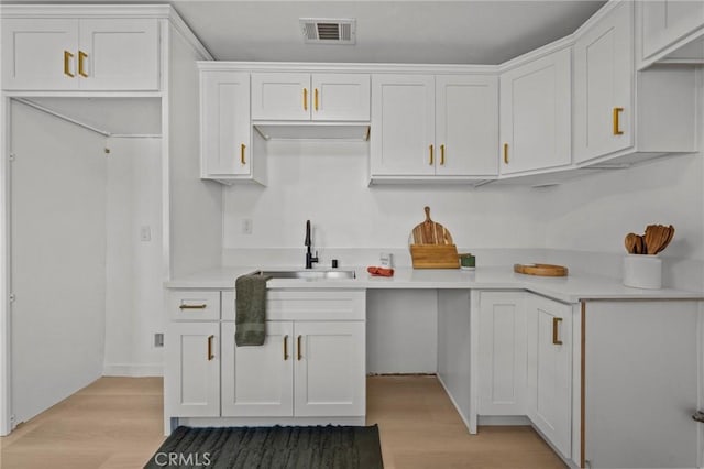 kitchen with white cabinets, light hardwood / wood-style flooring, and sink