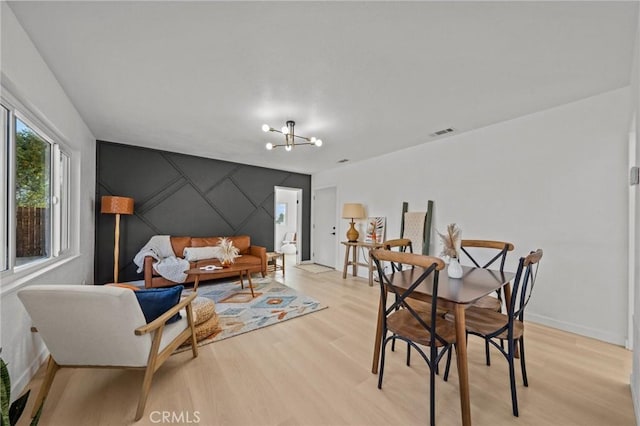 dining space with light hardwood / wood-style floors and an inviting chandelier