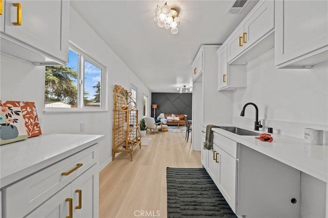 kitchen featuring white cabinets, light hardwood / wood-style flooring, and sink