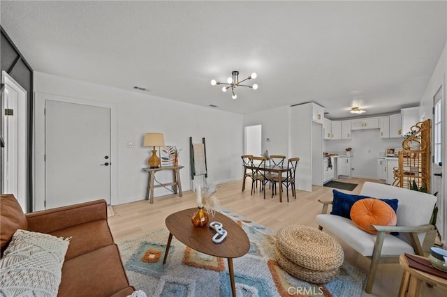 living room featuring a chandelier and light wood-type flooring