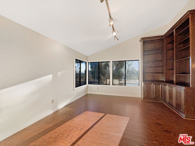 unfurnished living room featuring lofted ceiling, dark wood-type flooring, and rail lighting