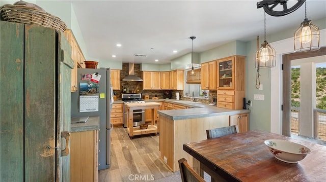 kitchen featuring backsplash, wall chimney exhaust hood, light brown cabinetry, light hardwood / wood-style floors, and stainless steel appliances