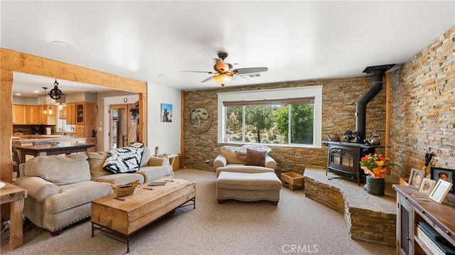 carpeted living room with ceiling fan with notable chandelier and a wood stove