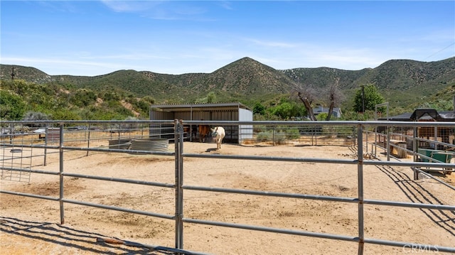 view of horse barn featuring a mountain view and a rural view